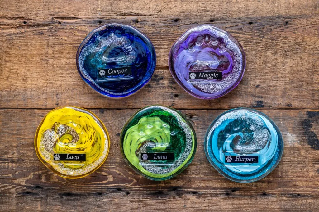 four different colored glass bowls sitting on top of a wooden table