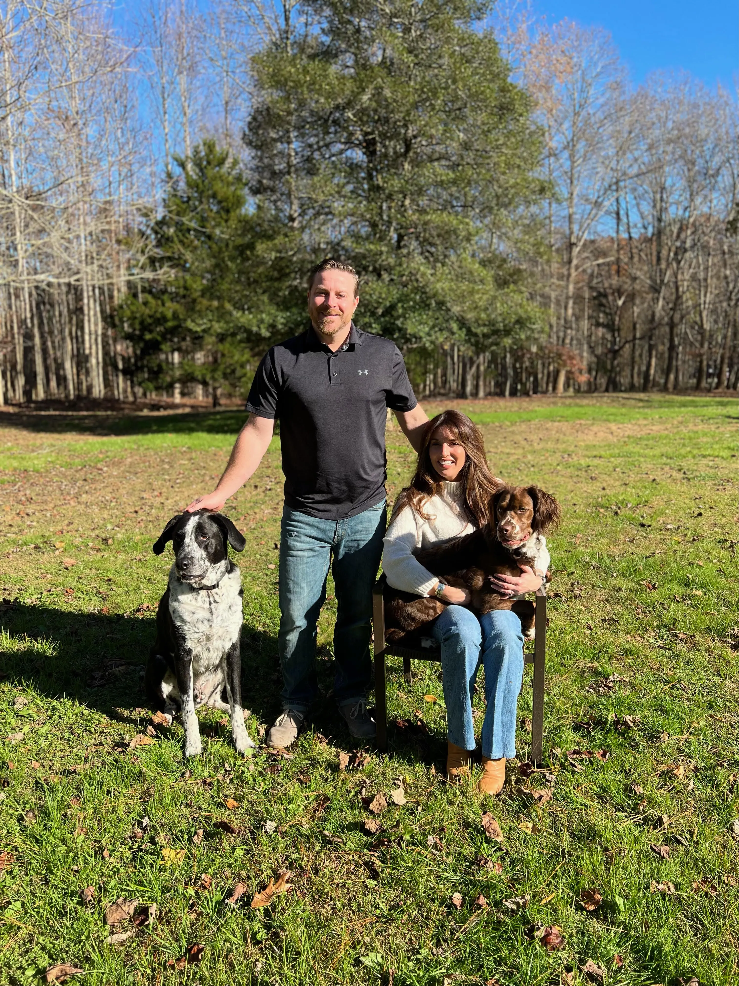 a man and woman sitting in a chair with two dogs