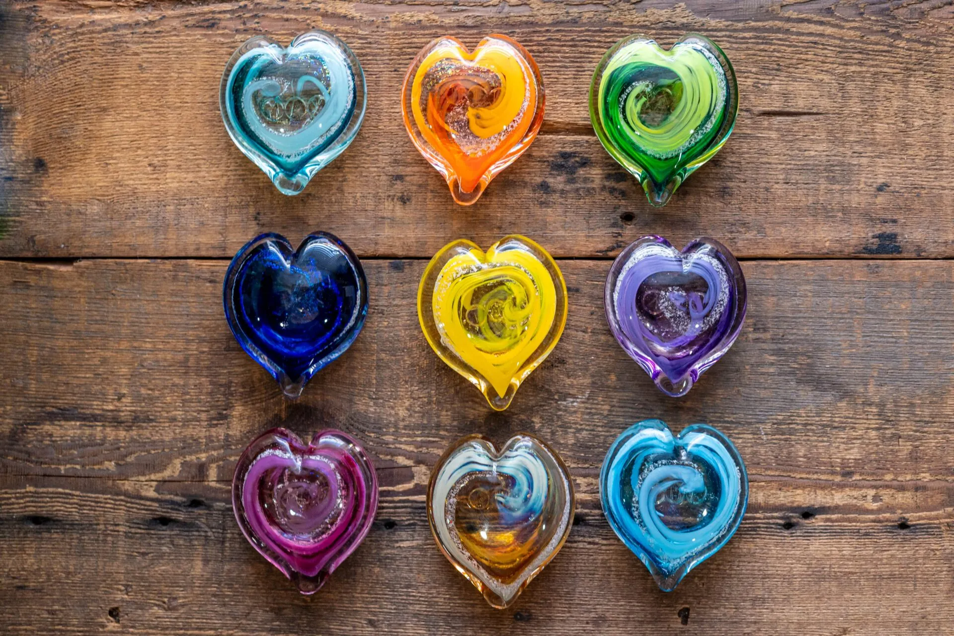 seven heart shaped glass dishes sitting on top of a wooden table