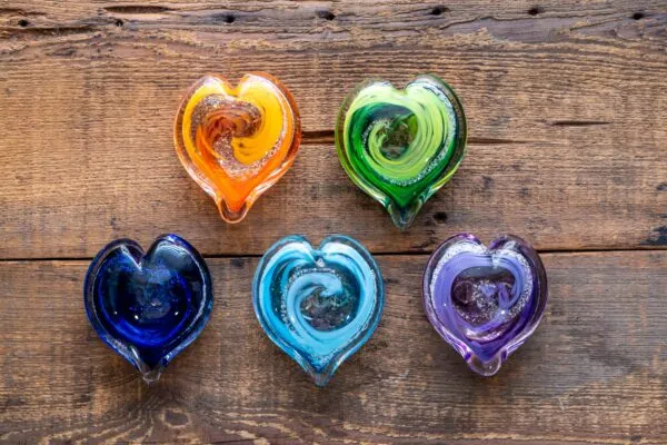 four heart shaped glass bowls sitting on top of a wooden table