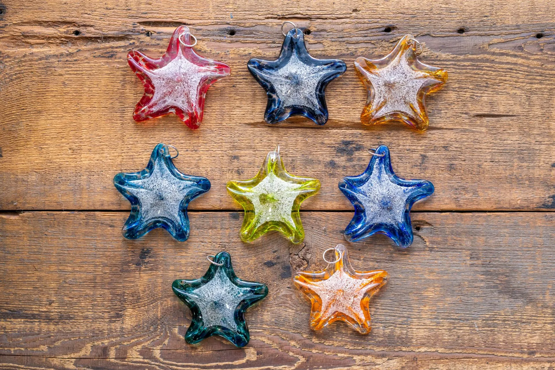 six glass stars are arranged on a wooden surface