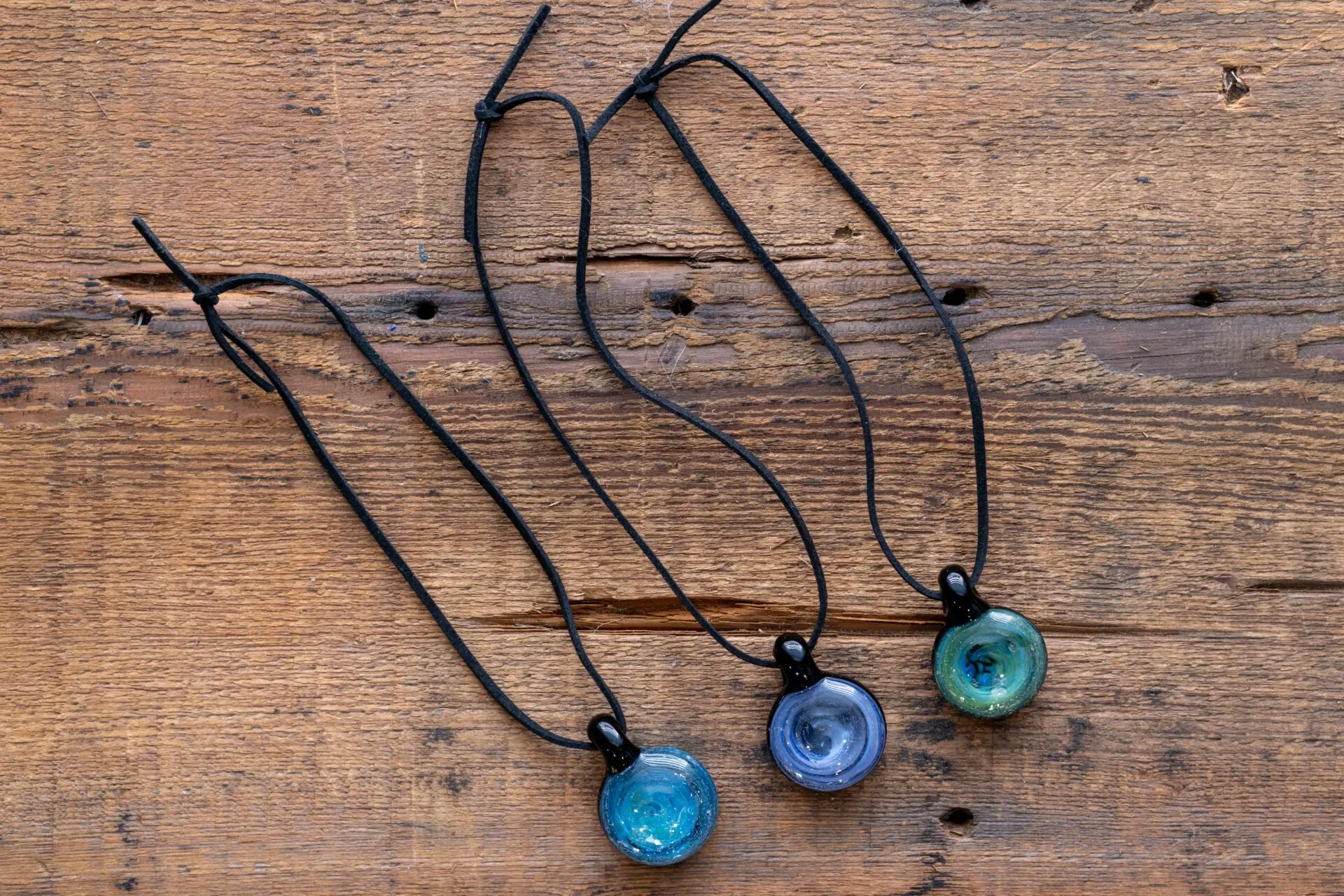 three necklaces are hanging on a wooden surface