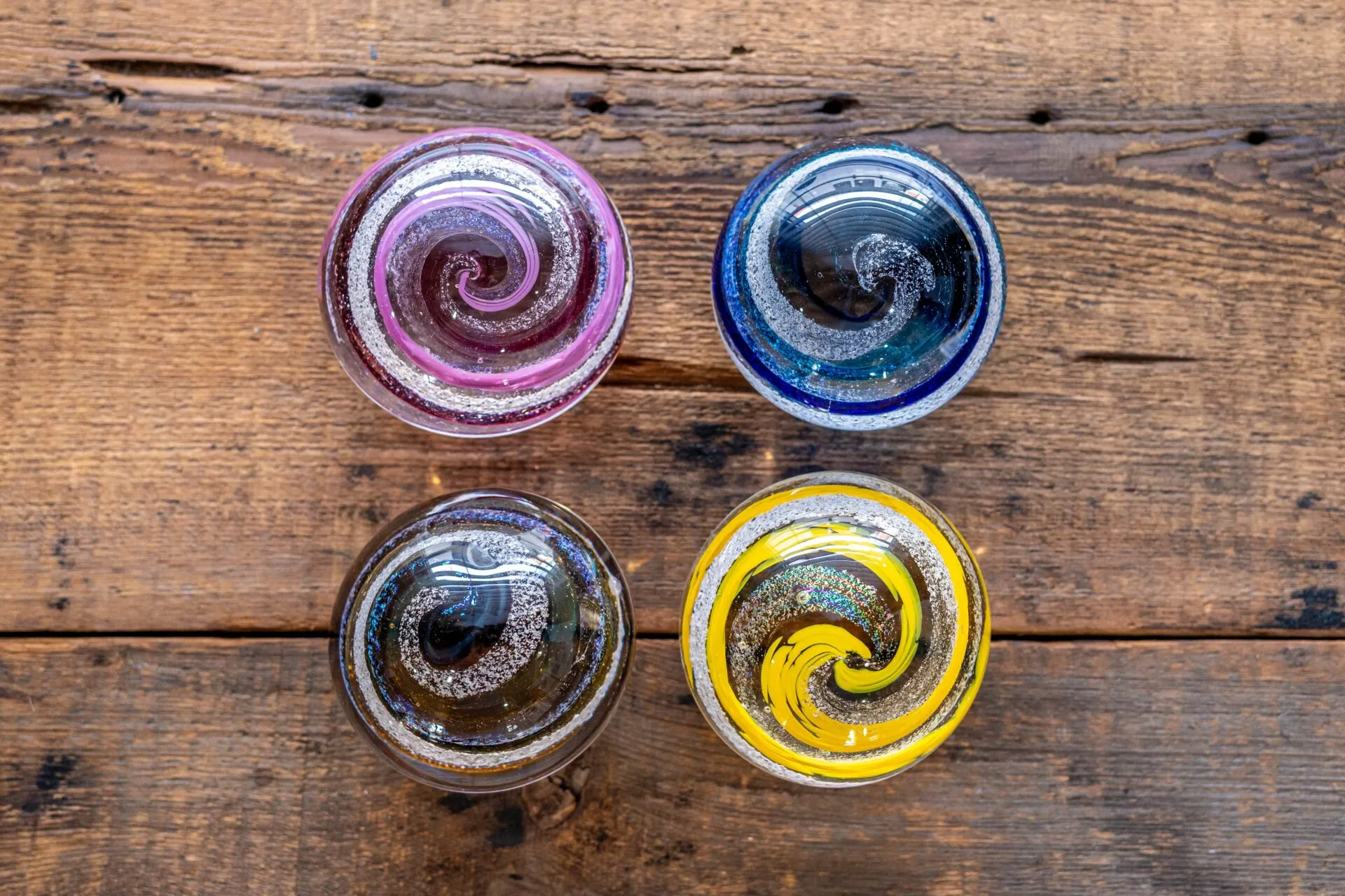 four different colored glasses sitting on top of a wooden table