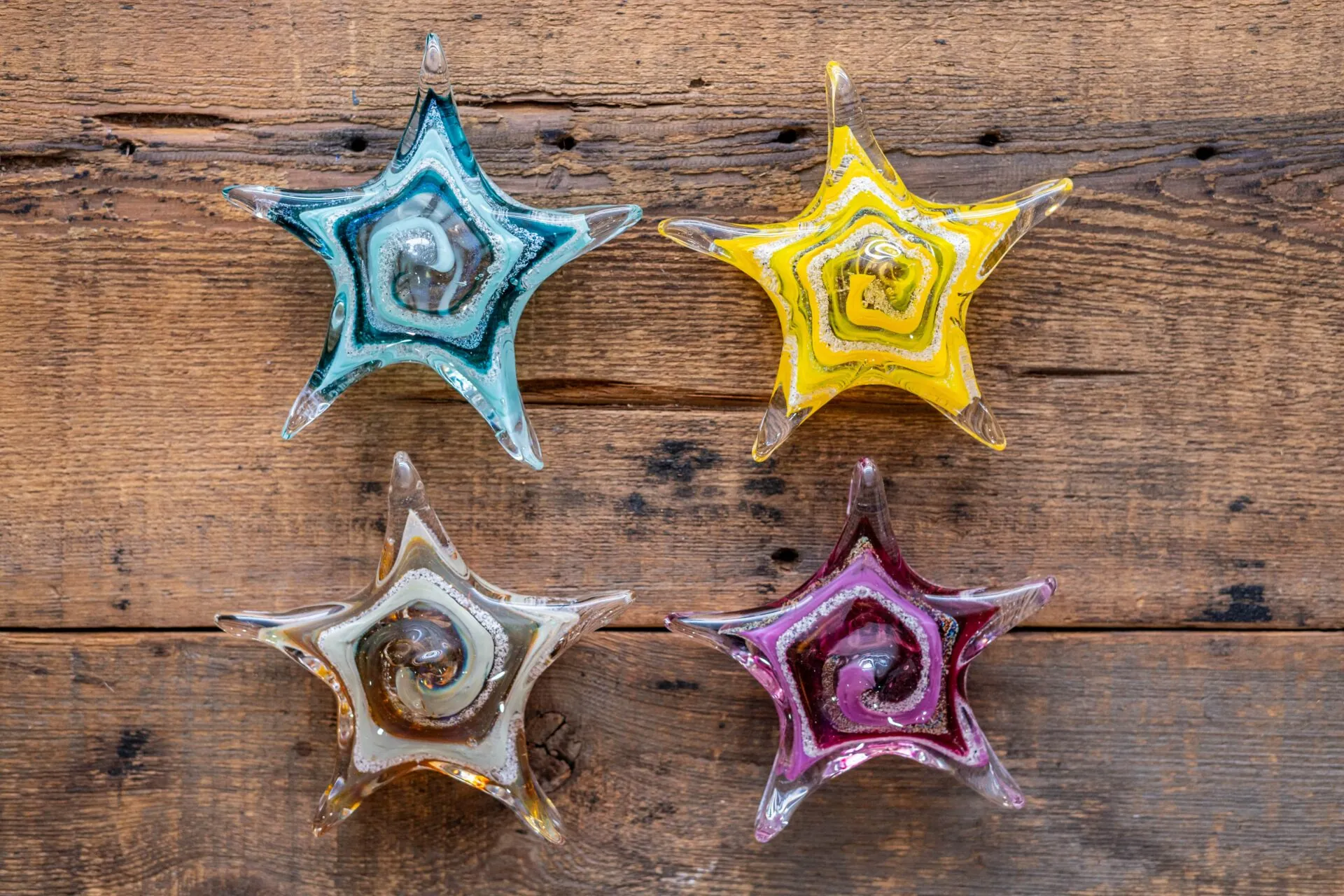 four colorful glass stars on a wooden surface