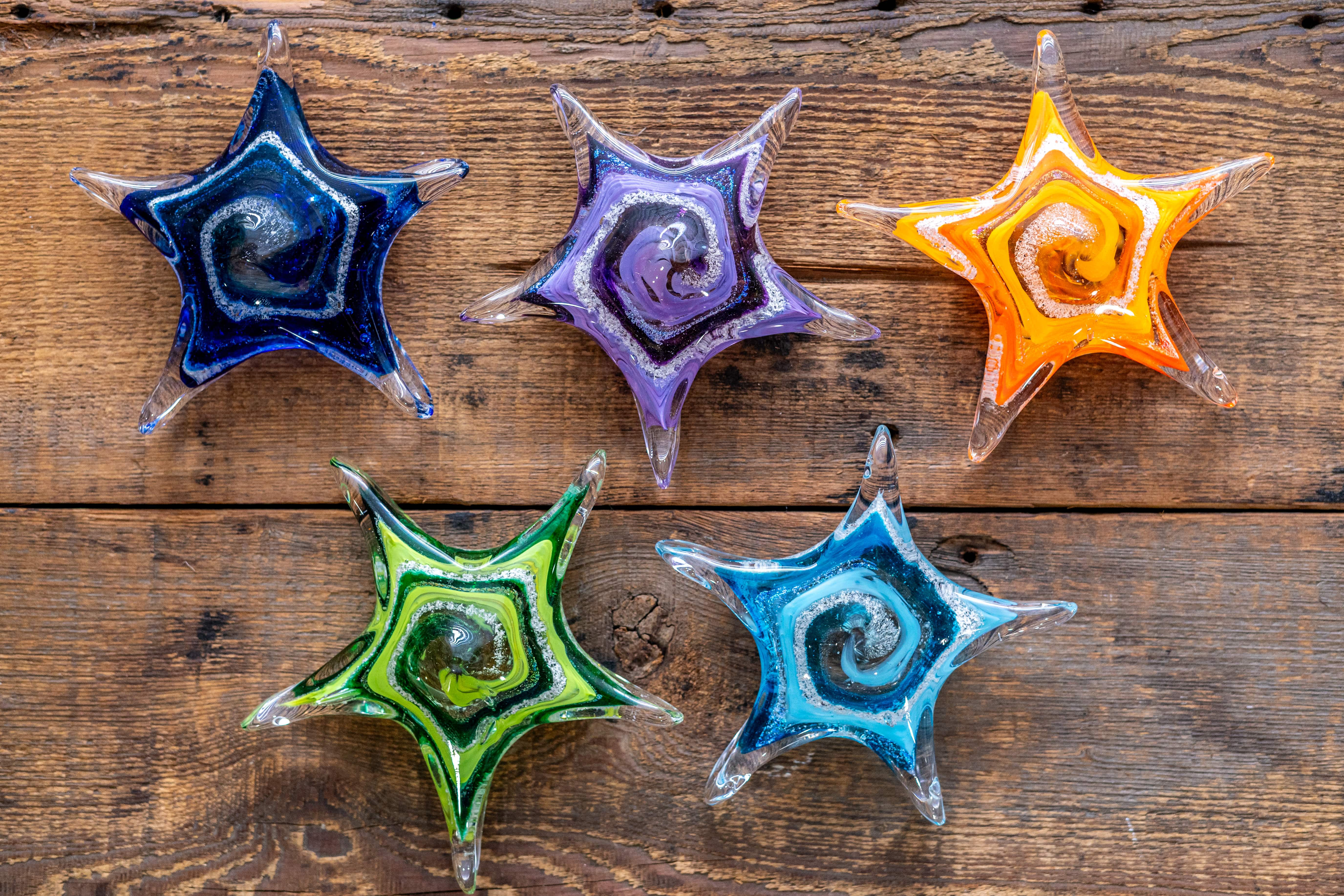 four colorful glass stars on a wooden surface